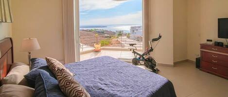 Bedroom with an exercise bike, TV, and an awesome ocean view