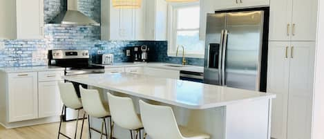 Cooking is a pleasure in this bright, beautiful and well-stocked kitchen that includes a large island, plenty of cabinet space, a pantry for your groceries, and beautiful wave-like tiles.