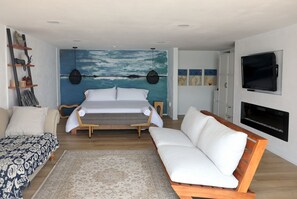 The spacious bedroom with a TV, seating area, fireplace and radiant heat floors