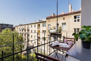 A view of a balcony overlooking a courtyard and neighboring residential buildings.
