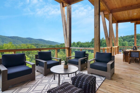 Outdoor living area with a cozy fireplace, plush seating, and mountain views