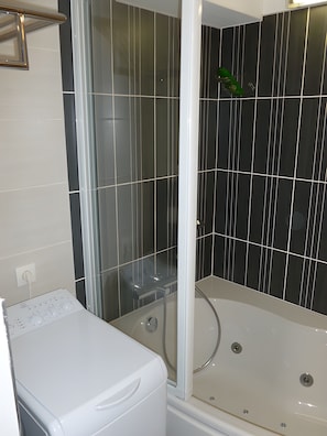 baignoire avec paroi de douche et machine à laver