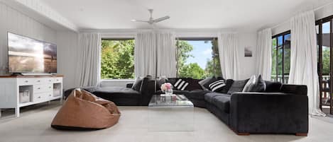 Spacious living room with huge couch, bean bags and 65-inch TV.