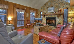 Cozy living room with a stone fireplace, comfy seating, and scenic views.