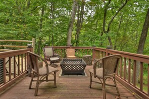 Private deck surrounded by lush trees and a central fire pit.