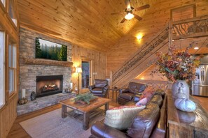 Rustic living room with stone fireplace and leather seating.