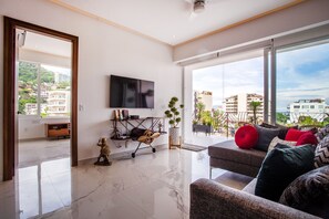 Living room has a huge smart TV and a comfy sofa