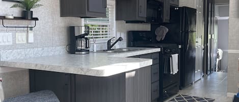 Full kitchen with bar, table and smart tv.