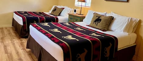 Two comfortable Queen beds with extra pillows and a night stand