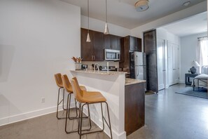 Fully stocked kitchen with basic cooking essentials, stainless steel appliances, granite countertops, and breakfast bar seating.
