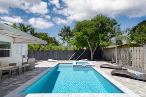 A beautiful backyard with a pool, hot tub, and lounge space.