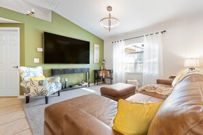 Living area with a view of the 85 inch flat panel TV, desk and palm chair