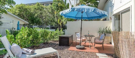 Open outdoor patio with a cafe style table, umbrella and two loungers. Beach items included.