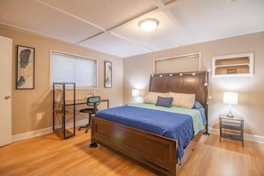 Bedroom, with queen size bed, side tables with lamps, laptop-friendly workspace, window to the outside with blind.