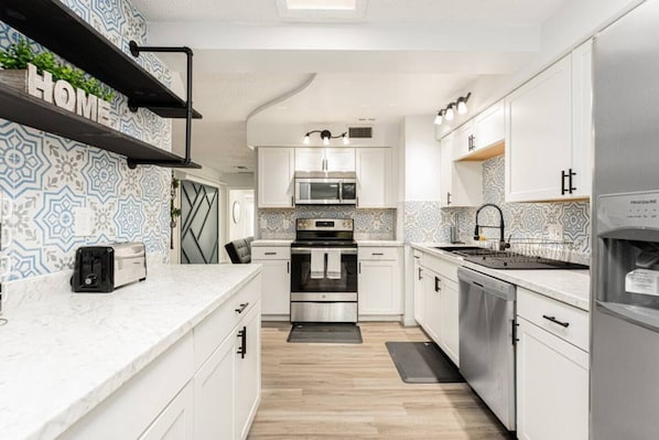 kitchen with cabinets, microwave, 4-burner stove with oven and large refrigerator
