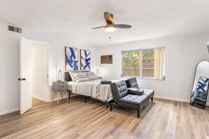 Modern and cozy space with a bed, sofa, desk, and a small integrated kitchen, decorated with minimalist details