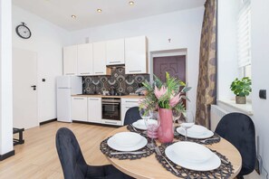 A kitchen and dining area with a white and black color scheme. The dining table is set for four with flowers as a centerpiece.
