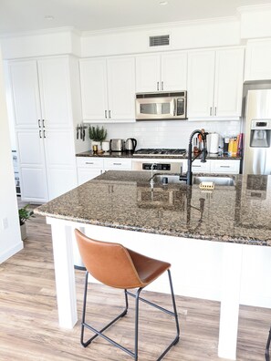 Stylish kitchen with marble island, seating for 4, and stainless appliances.