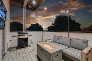 2nd unit: Rooftop patio with fire pit, outdoor bbq grill and lounge area draped in bistro lights.