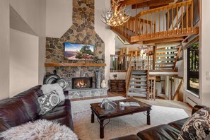 Main Living Room with plush, over-sized leather sectional, gas fireplace, smart TV, and private deck access