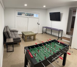 Game room with TV, foosball table and futon. Washer & dryer located here. 