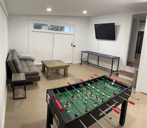 Game room with TV, foosball table and futon. Washer & dryer located here. 