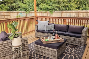 Spacious back deck with patio furniture and sun shade create a comfy atmosphere