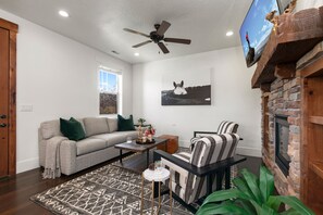 Living room with sofa, arm chairs, gas fireplace, and smart TV