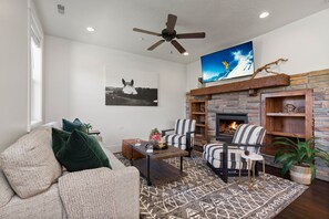 Living room with sofa, arm chairs, gas fireplace, and smart TV