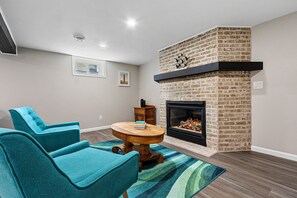 Basement living room area with electric fireplace, smart TV and air hockey table