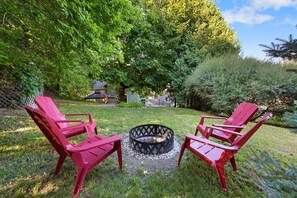 Private backyard features a 7 person hot tub under an all-weather awning, firepit with Adirondack lawn chairs, gas grill  and a hammock