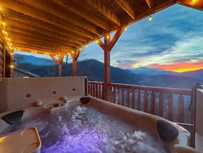 Soak in the hot tub under a vibrant sunset, offering relaxation with a view 