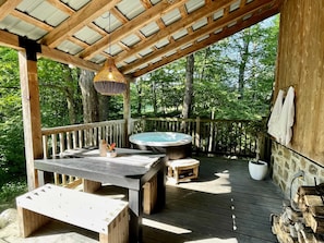 Terrasse extérieure équipée d’une table à manger et d’un spa