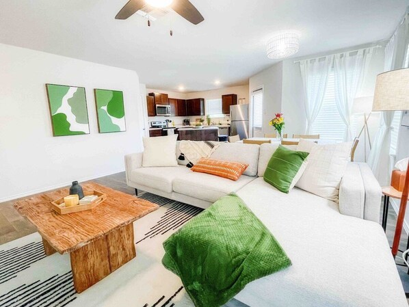 Large living room with plush light grey sofa and fluffy pillows. Custom wooden coffee table for you to feel cozy with all the throw blankets you could ask for!