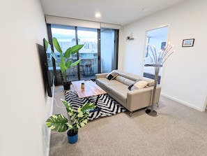 Living area with designer leather couch & coffee table and large screen smart TV