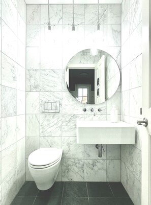 Luxurious main floor bathroom with marble walls, in wall toilet, slate floors