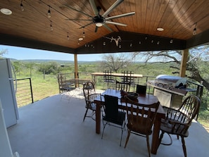 Back porch with lots of dining space, gas grill, refrigerator and TV.