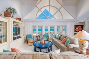 Embrace the light! ☀️ A grand living room with vaulted ceilings and 3 sets of glass doors, inviting the seascape inside.  #SereneViews