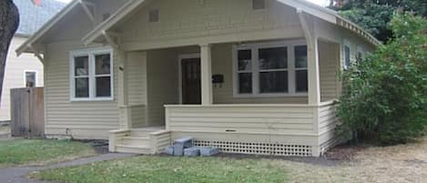 Front of home, covered front porch, lawn, curb-side parking.