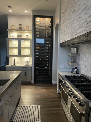 Kitchen with 12’ wall mounted wine rack along with 48” gas oven range. 
