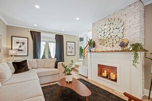 Elegant living room with sunny windows and stunning faux fireplace.