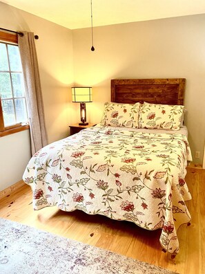 Upstairs master suite has a queen-sized bed looks out at the surrounding trees