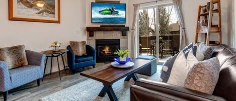 Living Room with gorgeous leather sofa, plush arm chairs, gas fireplace, smart TV, and private deck access
