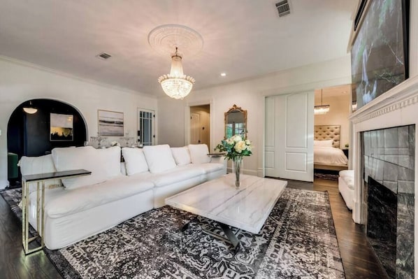 A refined living room adorned with a plush, cloud-like sofa that invites relaxation, complemented by the warm, timeless ambiance of a wood-burning fireplace, offering both comfort and elegance in perfect harmony.
