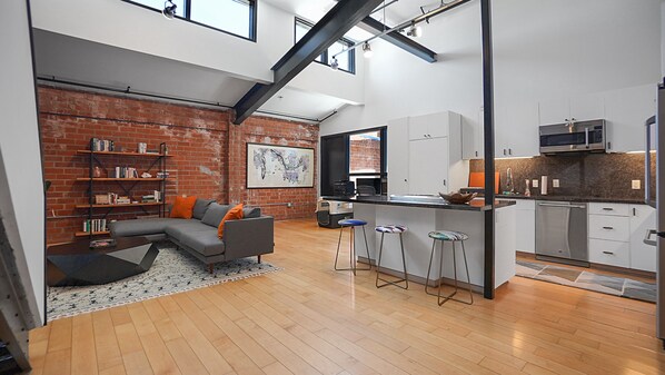 Modern loft with open floor plan, high ceilings, and tons of natural light. The washer and dryer are located in one of the tall cabinets behind the kitchen island.