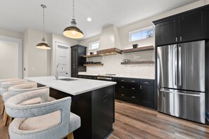 Large open kitchen with stainless steel appliances and quartzite counters.