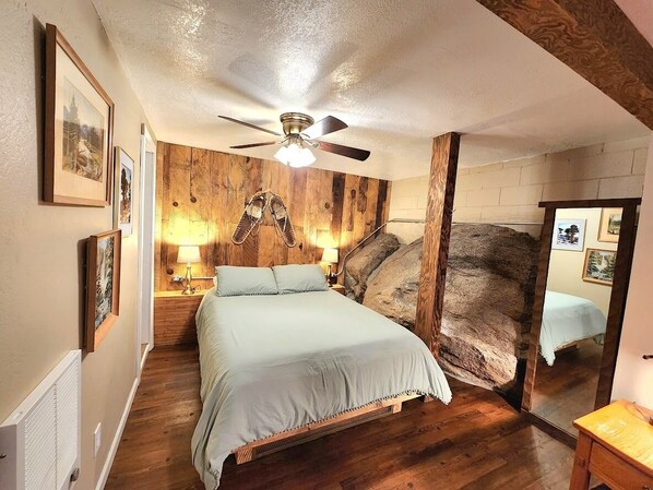 This unique bedroom includes a queen size bed, closet, and full size mirror. the bedroom area sits underground and has a huge granite rock coming out of the side of the wall! Linens and extra blankets are included in your stay.