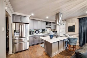 A fully equipped gourmet kitchen with a gas range, stainless steel vent hood, beautiful marble island and all the essentials, perfect for entertaining.