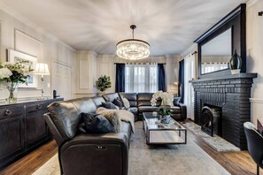 Relax in style in our living room, complete with a luxurious leather sectional, a charming brick fireplace, and bright, modern decor throughout, creating a sophisticated and inviting atmosphere.
