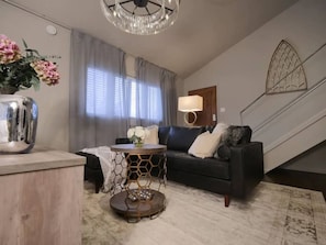 The open-concept living area features stylish seating, a large TV, and chic decor, all arranged around a cozy fireplace. It’s the perfect space to relax and unwind in a bright, inviting atmosphere